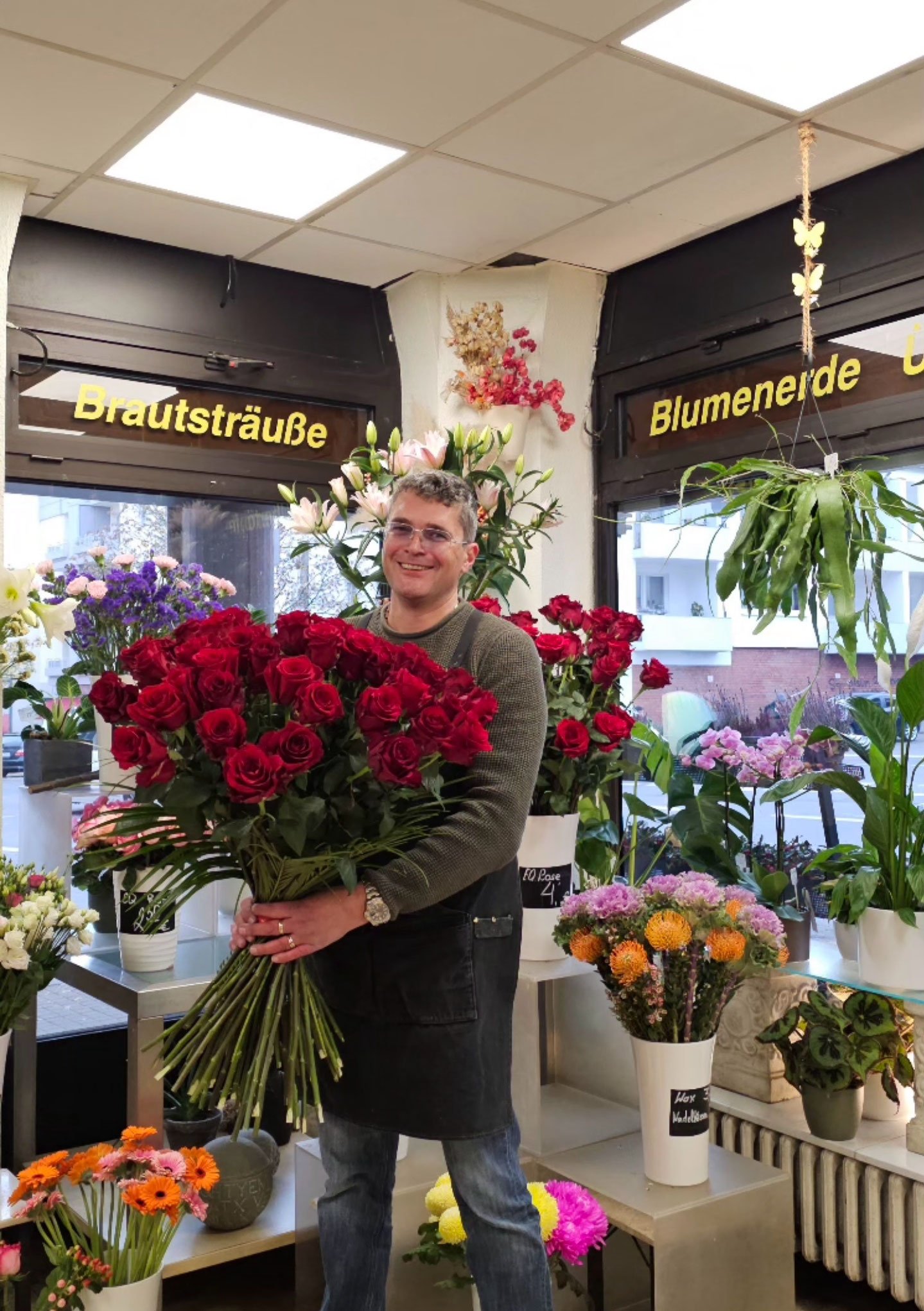 Inhaber der Vingster Blumen Ecke mit einem großen Strauß roter Rosen im Laden